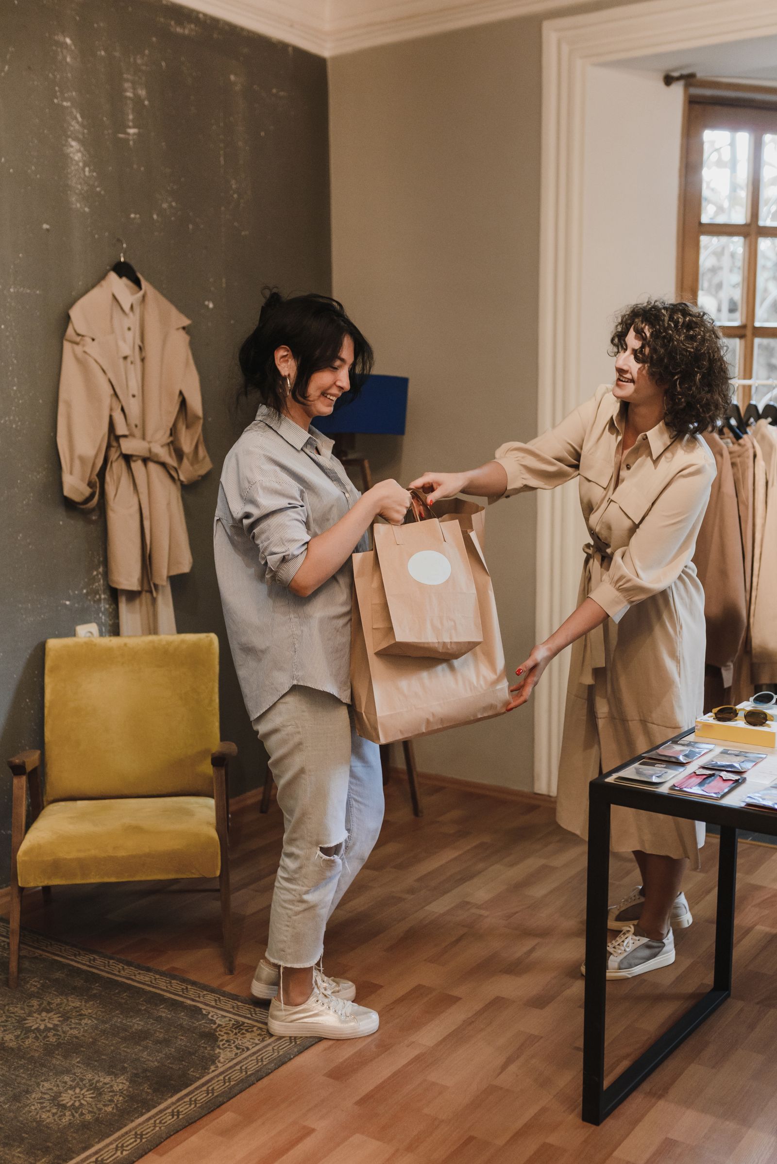 Cliente em loja de roupas com sacolas na compra, ilustrando o cartão de loja