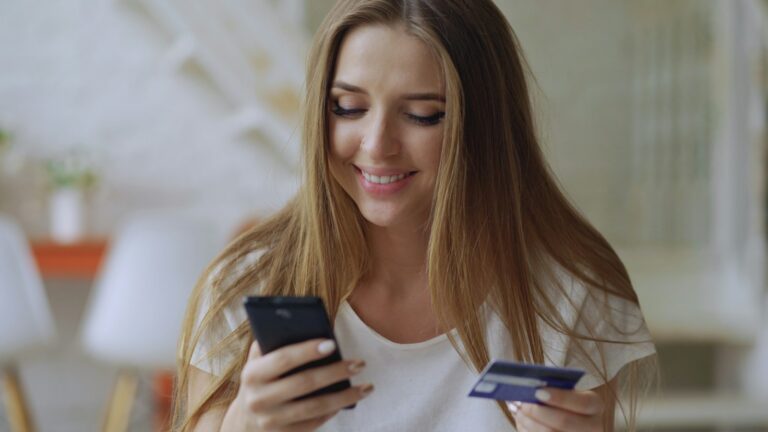 Cartão virtual: mulher usa o celular e o cartão para fazer uma compra pela internet