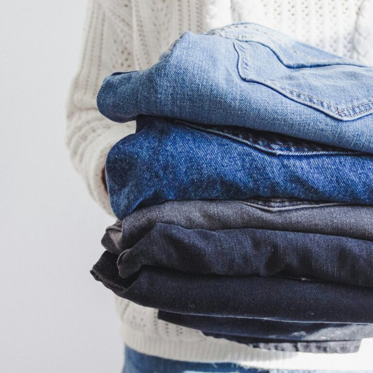 Pilha de calças jeans dobradas para mostrar como conservar roupas