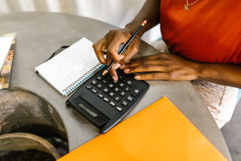 Mulher usando calculadora e caderno para planejar como economizar dinheiro
