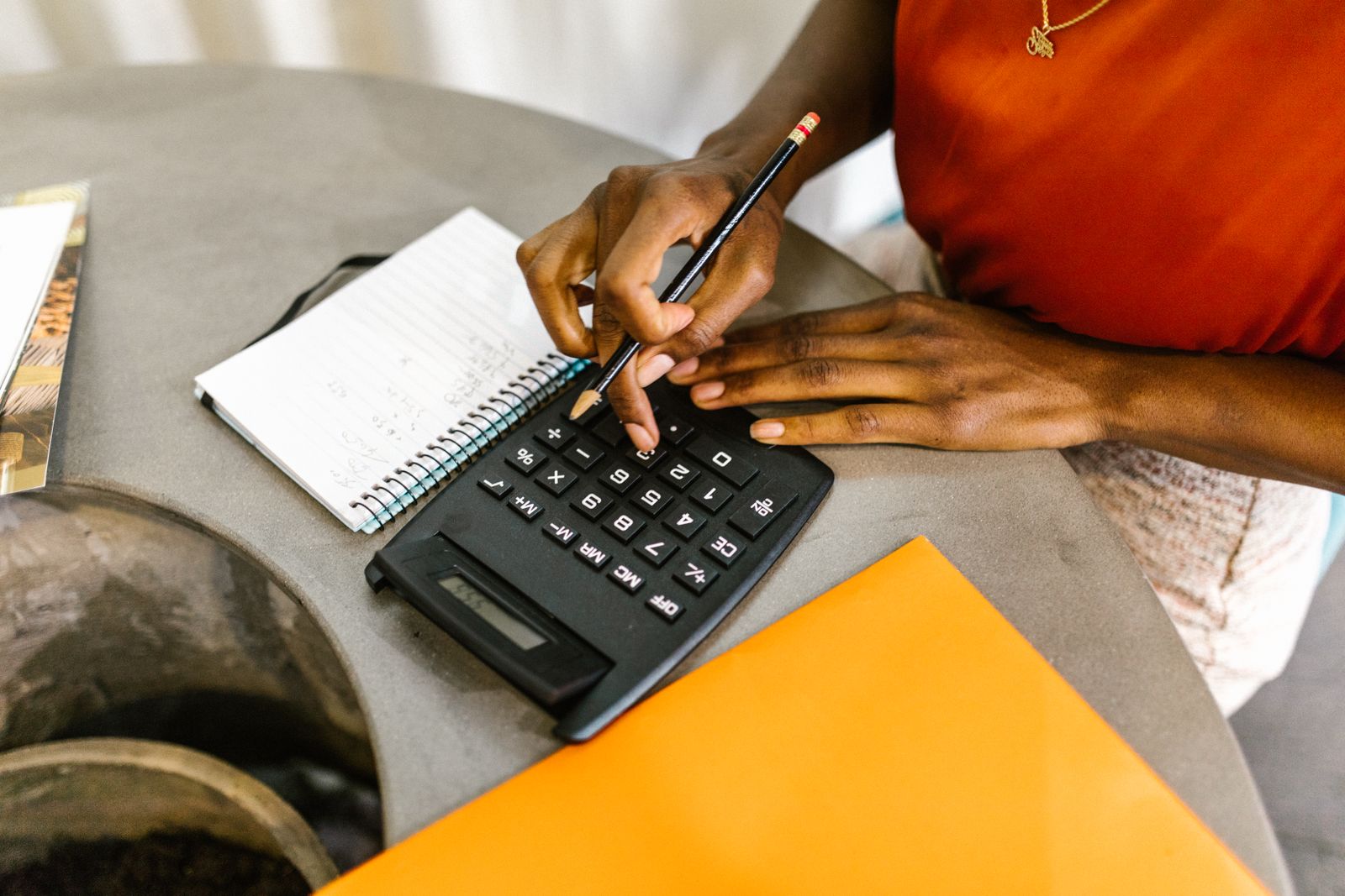 Mulher usando calculadora e caderno para planejar como economizar dinheiro