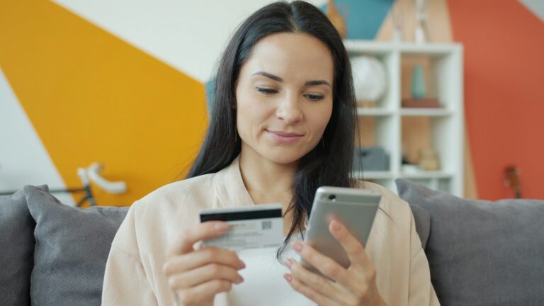 Mulher conferindo um cupom de desconto no celular antes de pagar com cartão