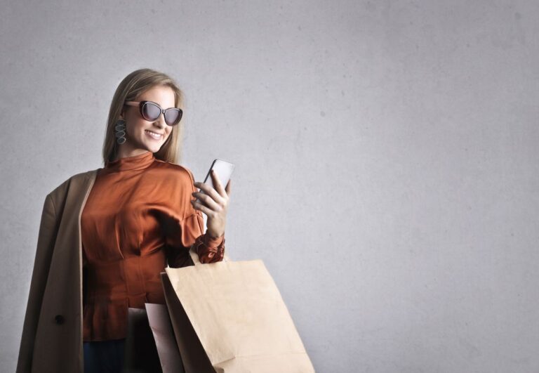 Mulher confere o celular antes de fechar a compra para não cair em descontos falsos