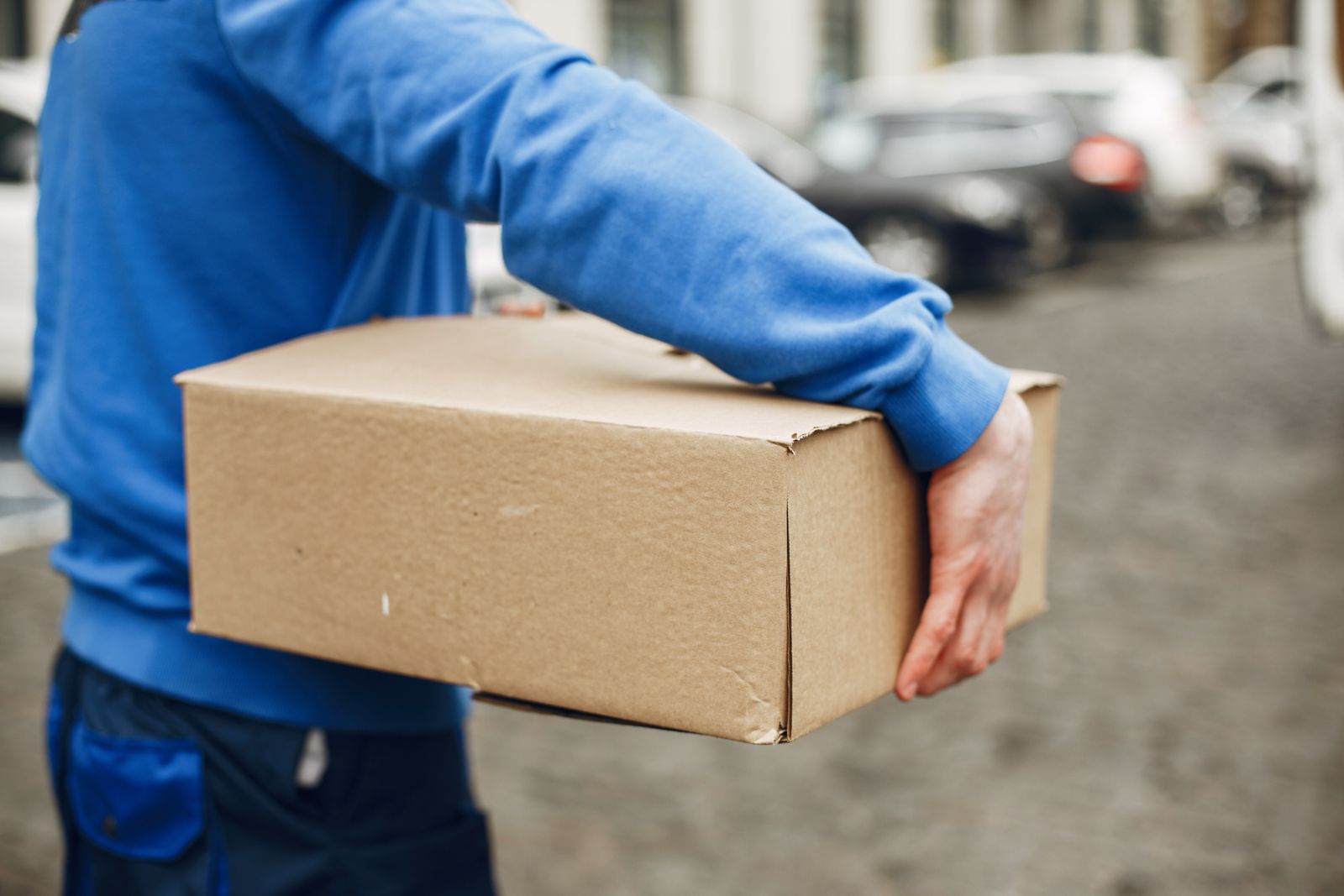 Entregador carregando caixa de papelão de uma compra com frete grátis