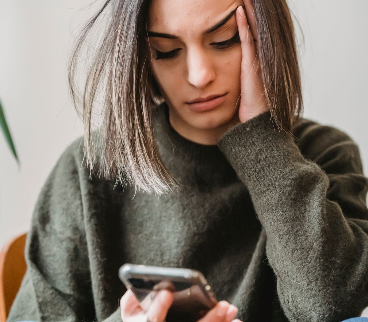 Mulher preocupada olhando o celular após suspeitar de golpes em compras online