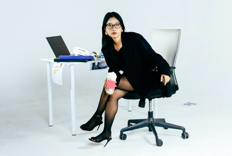 Looks para trabalho: mulher de blazer preto sentada à mesa do escritório