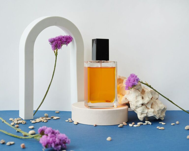 Frasco de perfume que fixa, com fragrância âmbar sobre pedestal e flores