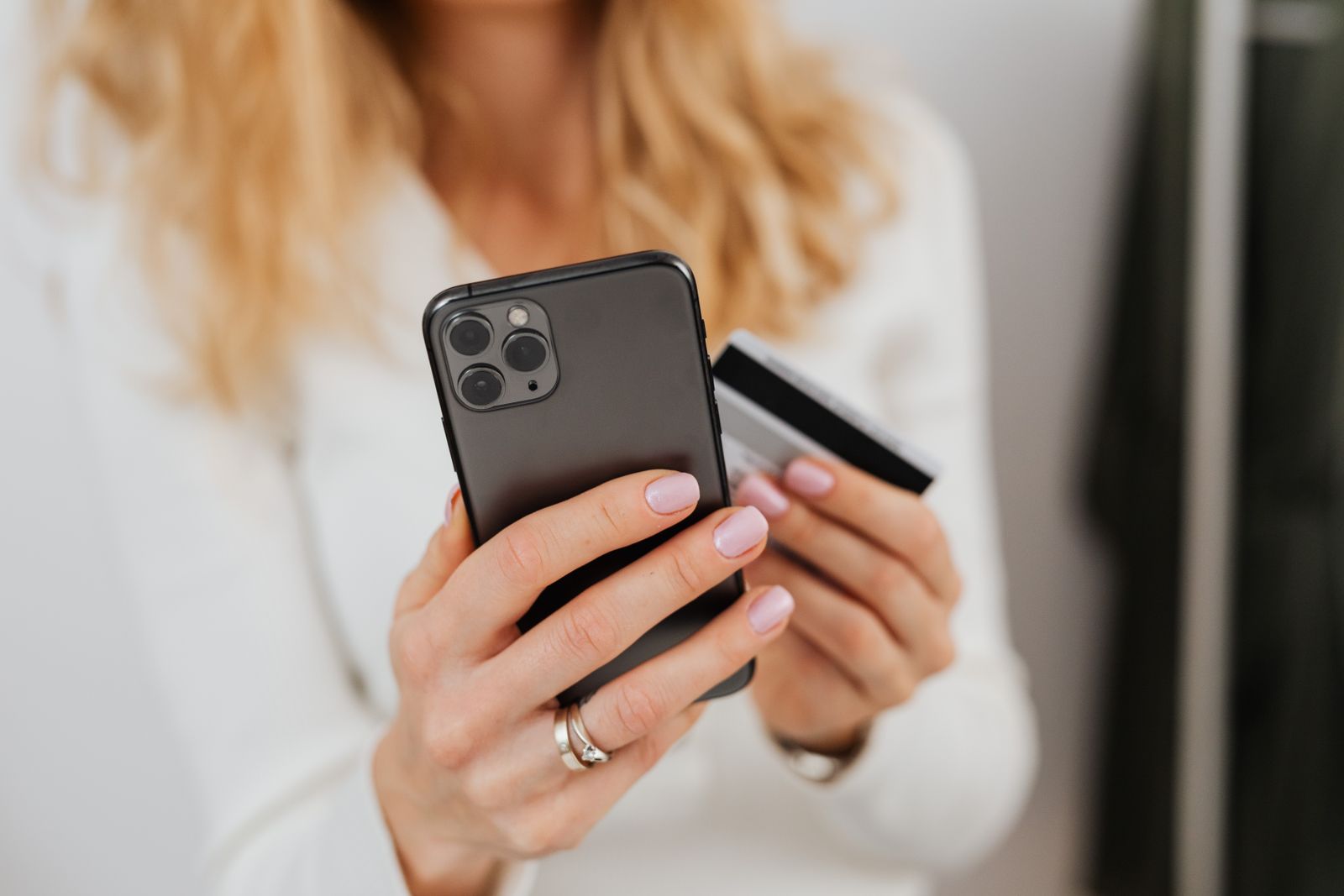 Mulher compara pontos ou cashback no celular com o cartão na mão