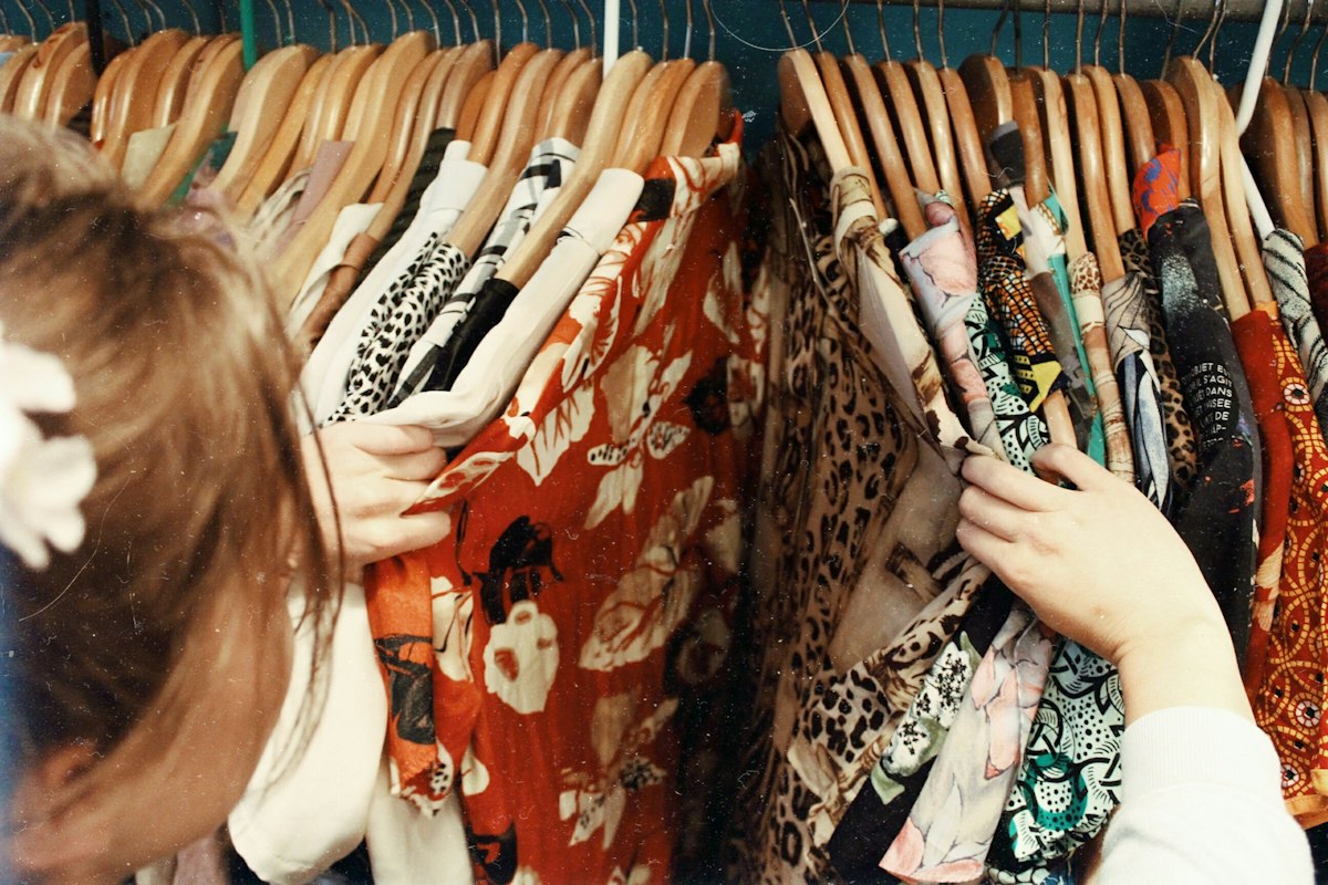Vender roupas usadas: arara de brechó com peças estampadas em cabides de madeira